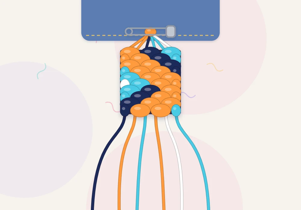 A zigzag bracelet in tangerine, navy, aqua and white being knotted, pinned at the top with loose strings below