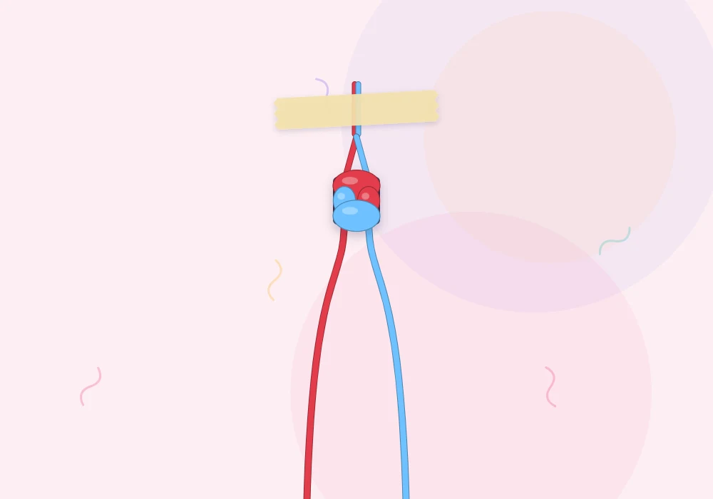 A red string and a sky blue string knotted together at the top and taped down, ready for practice