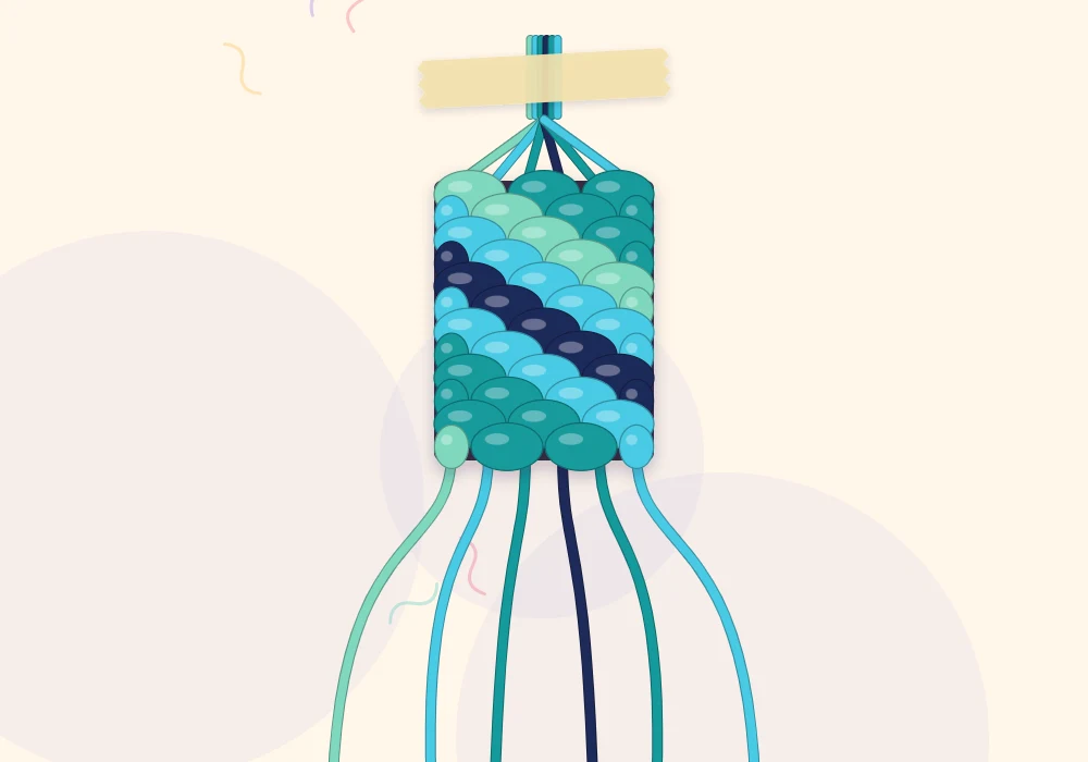 A candy stripe bracelet in progress taped at the top, with diagonal stripes shading from mint through aqua and teal to navy and back